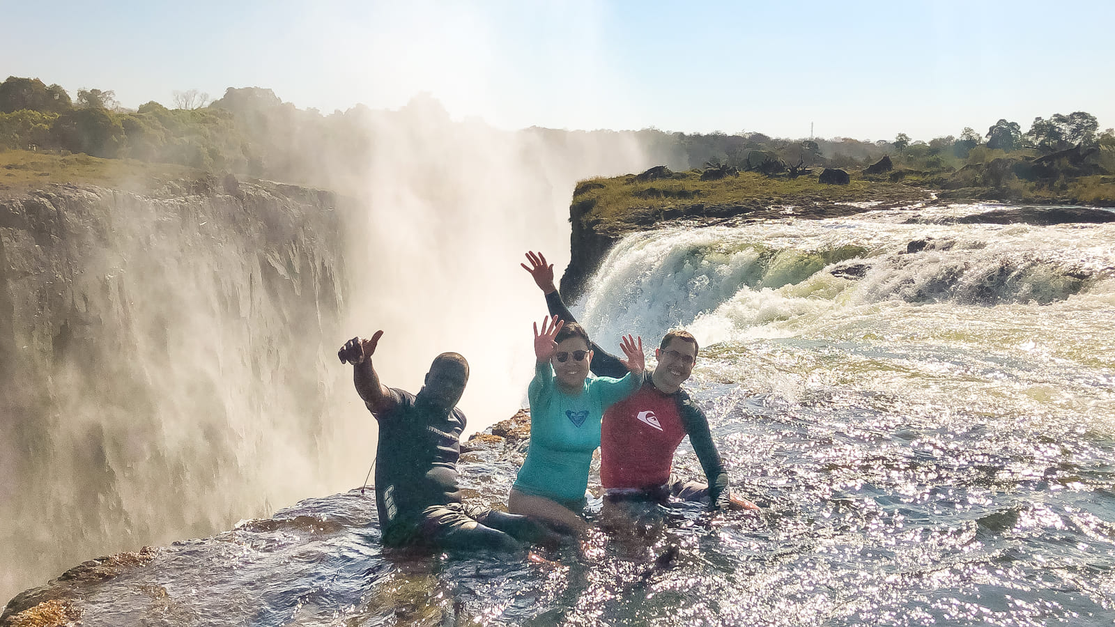 Julie and Carlos waving at Devil's Pool, Victoria Falls, Zambia