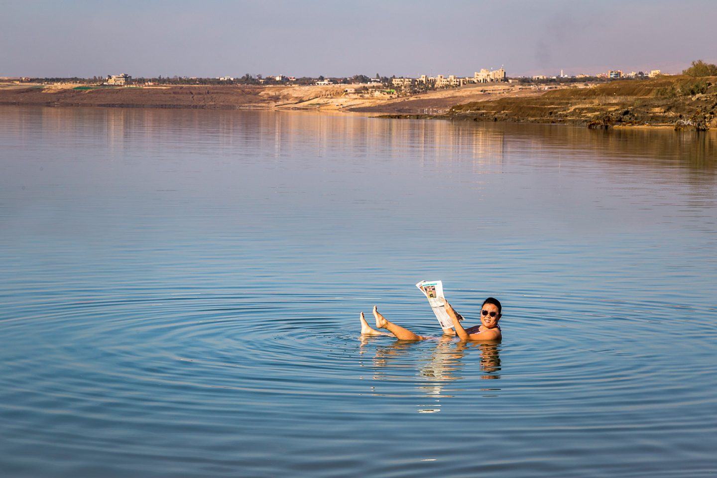 Reading a newspaper while floating in the Dead Sea, Jordan