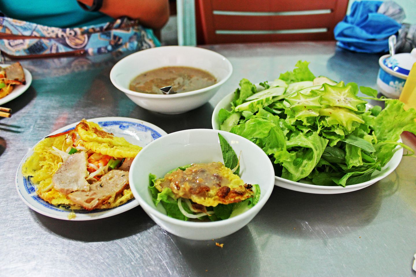 Creating a bowl of banh khoai with vegetables and sauce