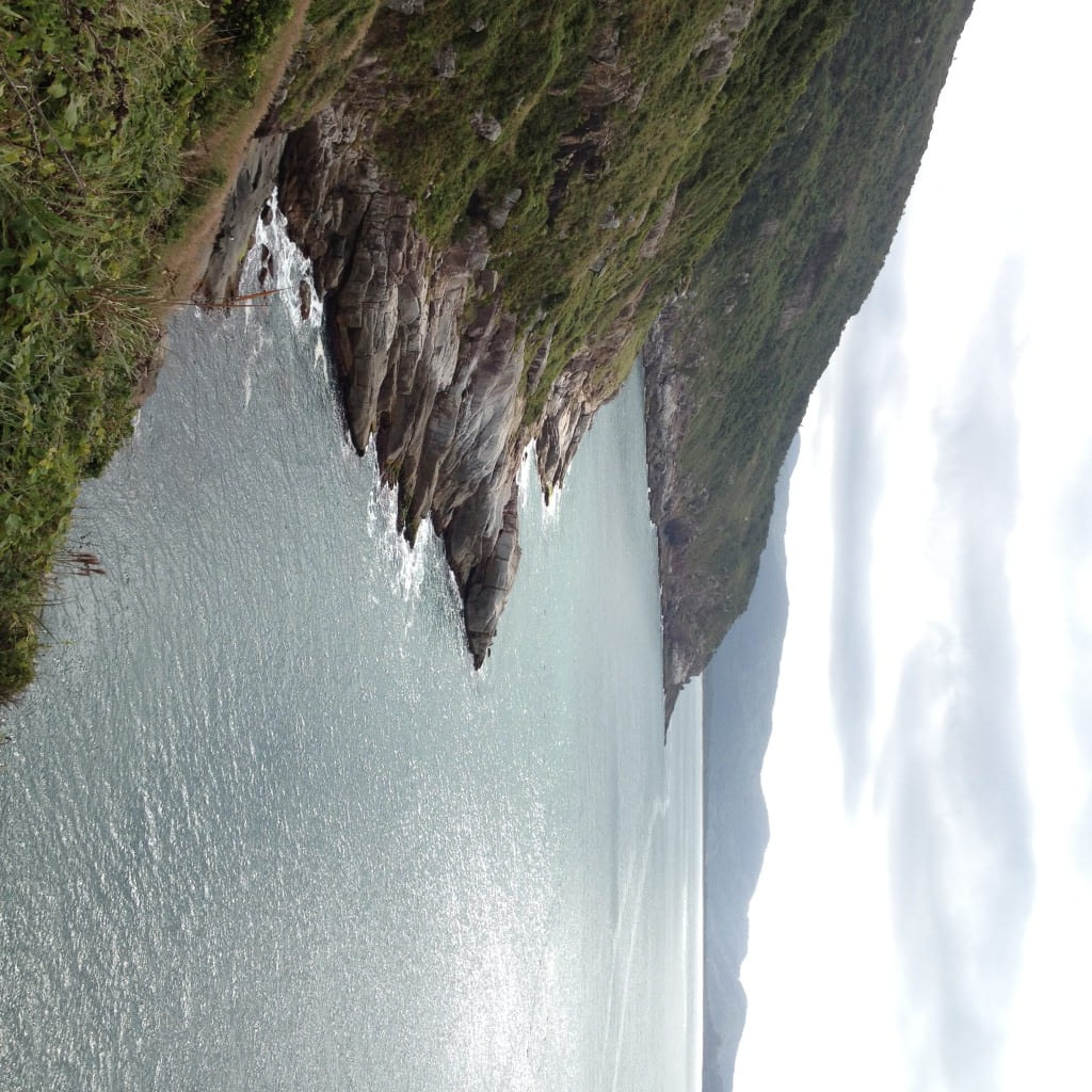 Clear views of rolling hills, rocky shores, and the ocean along the coast.
