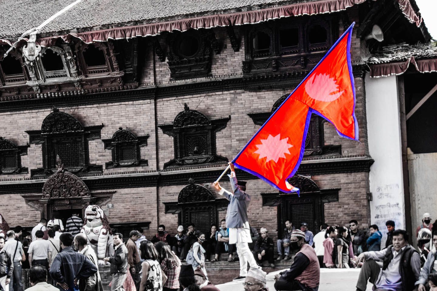 Local waving Nepalese flag at Kathmandu Durbar Square, Nepal