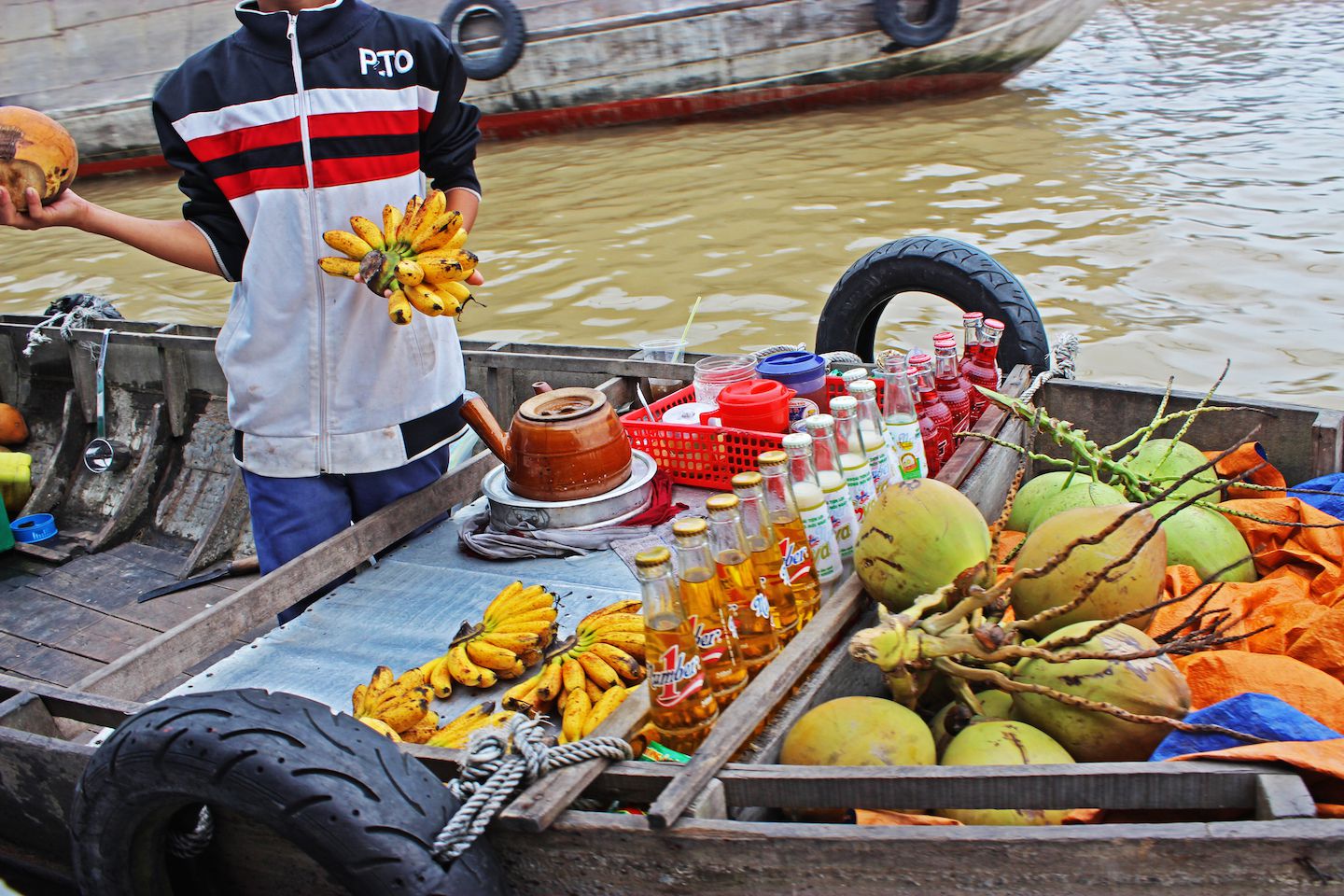 Vendors move around on boats trying to sell fruits and other goods